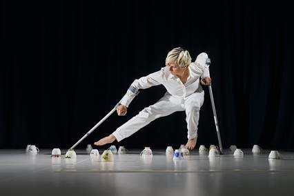Die schottische Performance-Künstlerin Claire Cunningham im weißen Hosenanzug tanzt mit zwei Krücken zwischen umgedrehten Porzellantassen auf der Bühne - Foto: Colin Mearns