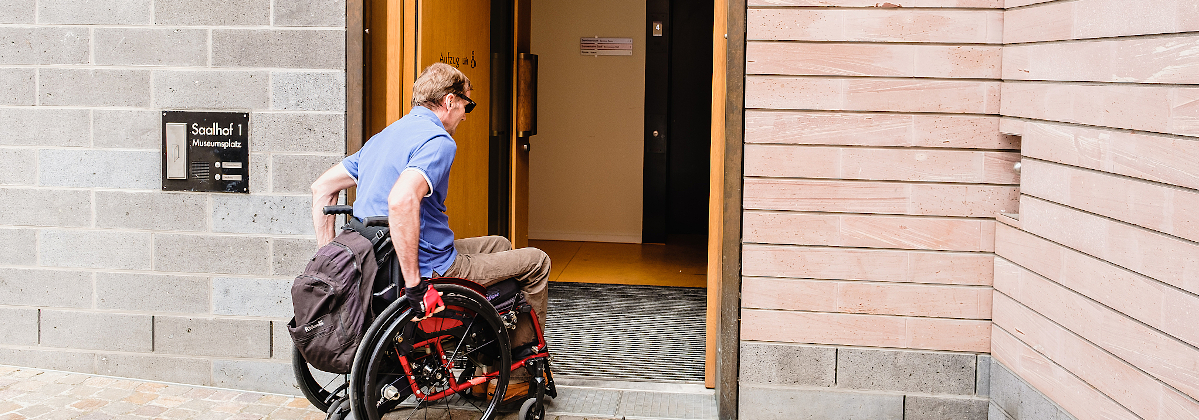 Rollstuhlfahrer vor einer breiten Tür