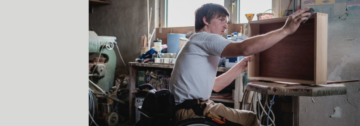 Junger Mann im Rollstuhl arbeitet als Tischler