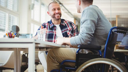 Ein Lotse unterstützt eine Person im Rollstuhl bei der Arbeit.