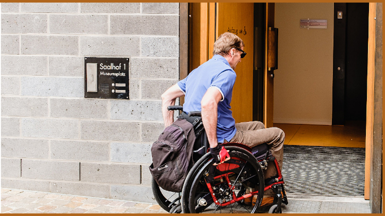 Ein Rollstuhlfahrer vor einer breiten Tür ohne Stufen; Bild: Andi Weiland I Gesellschaftsbilder