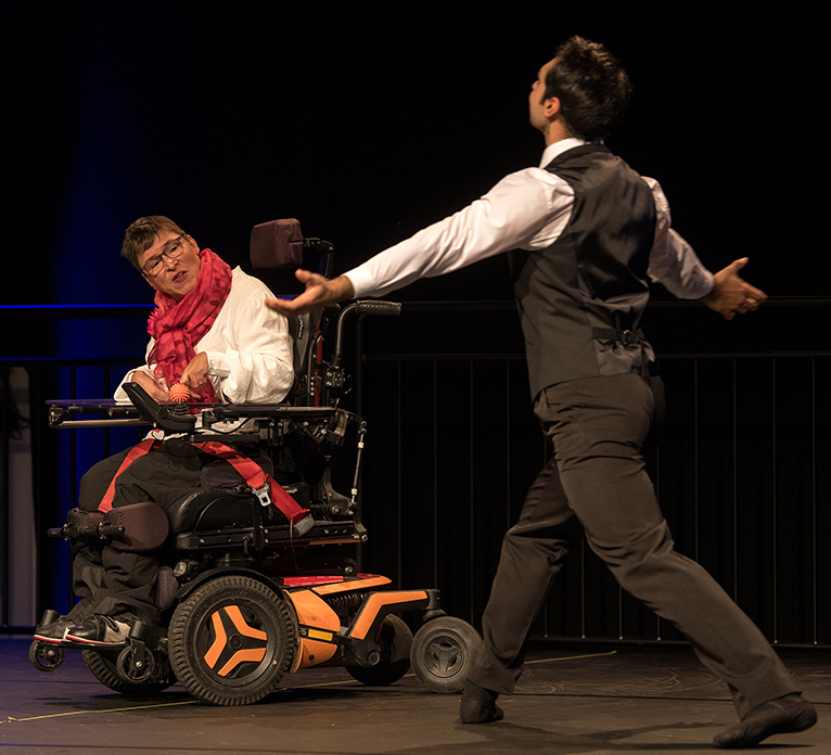 Eine Dame im E-Rolli gemeinsam mit einem Tänzer des Aalto Ballett Essen