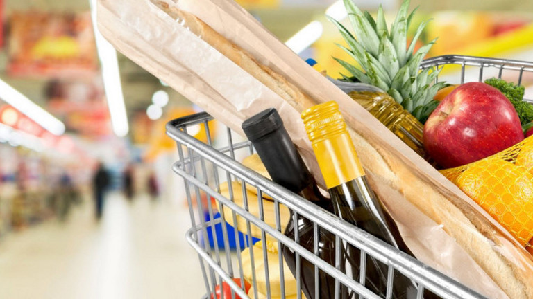 Das Bild zeigt einen vollen Einkaufwagen mit verschiedenen Lebensmitteln in einem Supermarkt. 