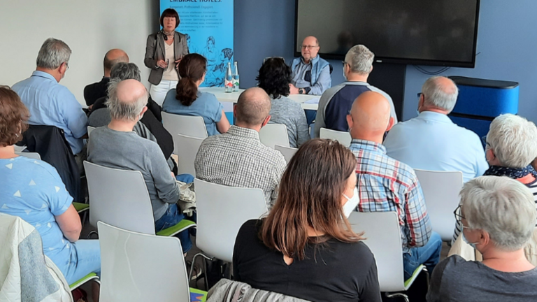 vorne: Margit Benemann, Geschäftsführerin von Pro Mobil und Rechtsanwalt Norbert Bonk; eine Gruppe von Zuhörer*innen