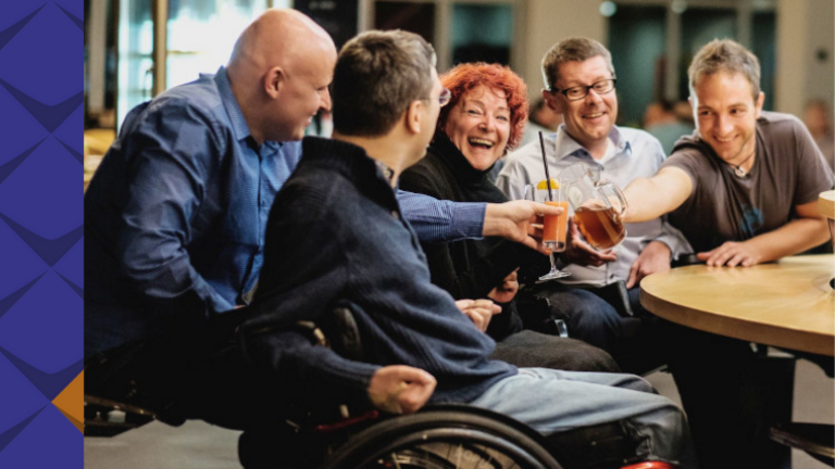Mehrere Personen sitzen in fröhlicher Atmosphäre um einen Tisch. 