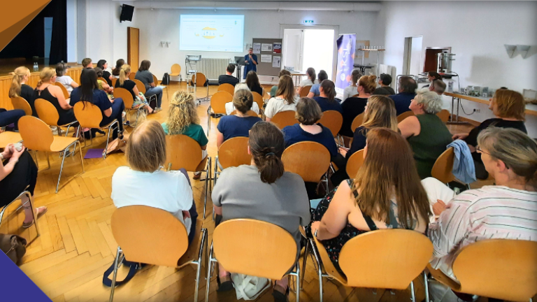Blick in den Saal mit zahlreichen Teilnehmer*innen in Düsseldorf-Benrath: vorne: Referentin Ulrike Häcker
